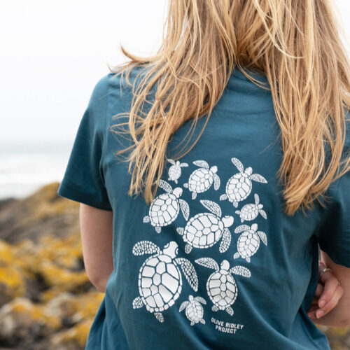 Female model wearing a sustainable T-shirt made from organic cotton and seaweed blend, featuring a sea turtle design on the back. Proceeds from sales support sea turtle conservation. Image.