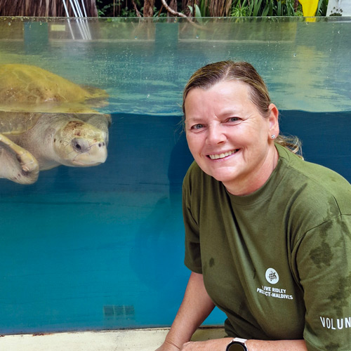 Sea turtle volunteer Nicola Selby in front of a turtle patient tank at the Marine Turtle Rescue Centre in Maldives. Image.